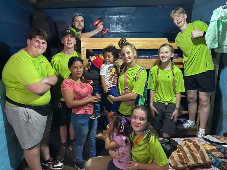 Children and volunteers by a new bunk bed