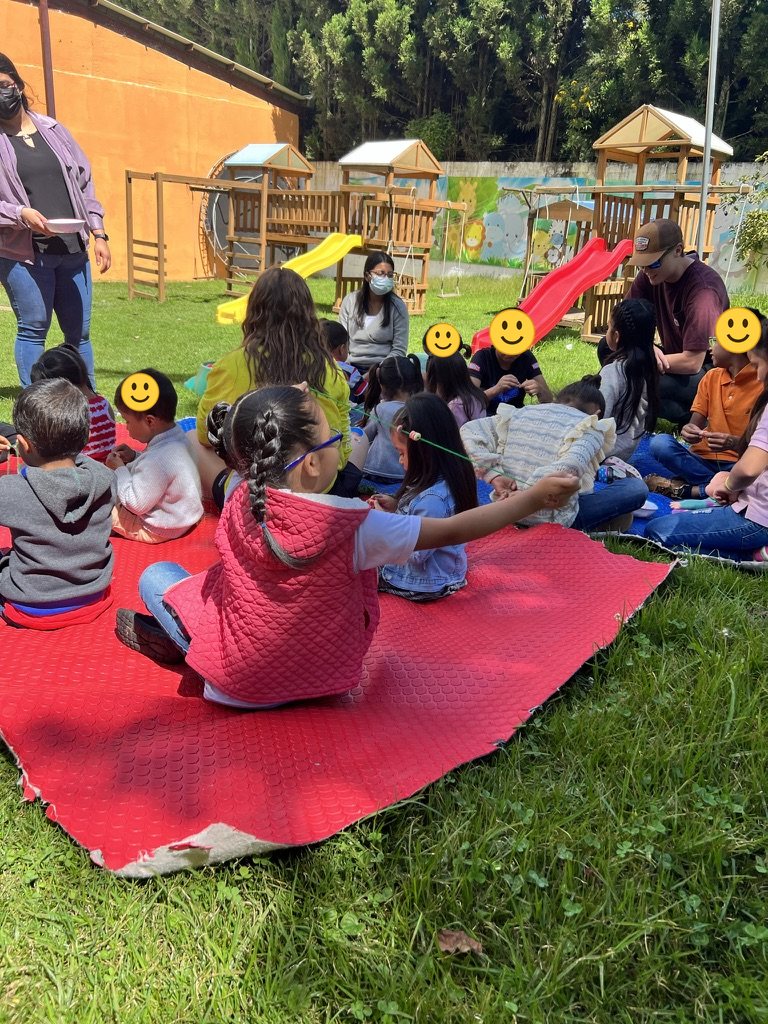 Children and volunteers on a blanket by the playground
